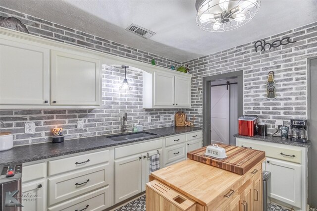 202 E Ross St, Rising Star, TX 76471 - kitchen with a sink, butcher block counters, white cabinets, brick wall, and a kitchen island