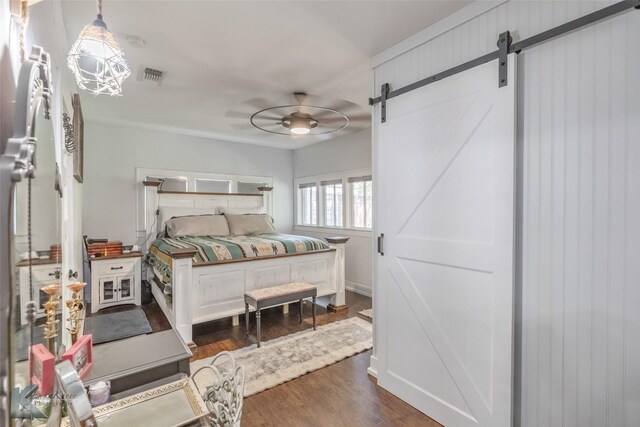 202 E Ross St, Rising Star, TX 76471 - bedroom with a barn door, dark wood-style flooring, and a ceiling fan