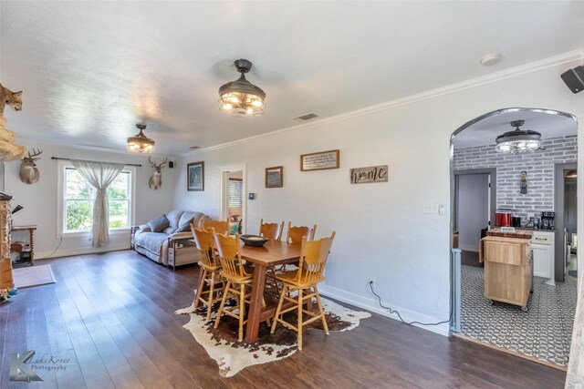 202 E Ross St, Rising Star, TX 76471 - dining area with dark wood-style floors, arched walkways, baseboards, crown molding, and a fireplace