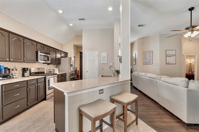 2700 Rochelle Dr, Mckinney, TX 75070 - kitchen featuring appliances with stainless steel finishes, a sink, a kitchen breakfast bar, lofted ceiling, and open floor plan