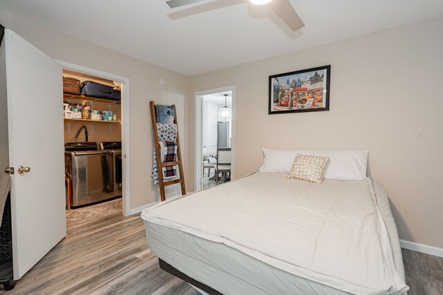 1100 Cartwright Ln, Kaufman, TX 75142 - bedroom featuring independent washer and dryer, wood finished floors, a spacious closet, baseboards, and a ceiling fan