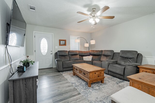 1100 Cartwright Ln, Kaufman, TX 75142 - living area featuring a ceiling fan, light wood-style flooring, a wainscoted wall, and a textured ceiling