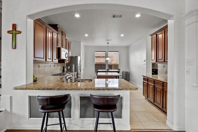 204 Leonard Way, Fate, TX 75087 - kitchen featuring stainless steel microwave, a sink, a peninsula, arched walkways, and tasteful backsplash