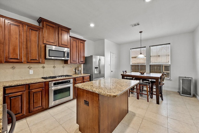 204 Leonard Way, Fate, TX 75087 - kitchen featuring stainless steel appliances, decorative backsplash, light stone counters, a center island, and decorative light fixtures