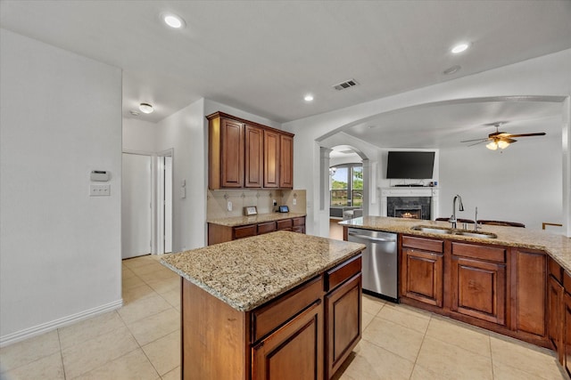 204 Leonard Way, Fate, TX 75087 - kitchen with stainless steel dishwasher, a sink, arched walkways, a ceiling fan, and light stone counters