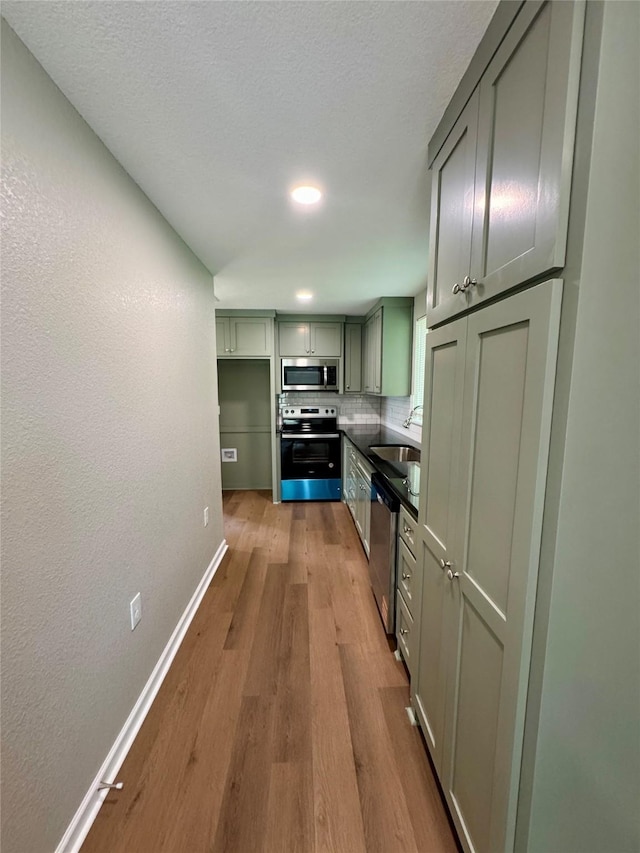 924 Gurley Ln, Waco, TX 76706 - kitchen with appliances with stainless steel finishes, a sink, baseboards, wood finished floors, and backsplash