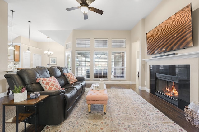10105 Hunter Run, Frisco, TX 75035 - living room with a tiled fireplace, ceiling fan, a chandelier, wood finished floors, and a high ceiling
