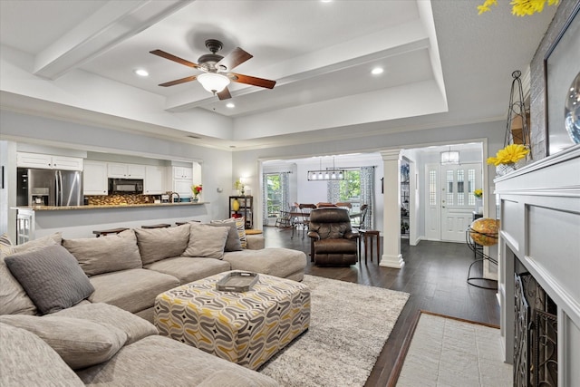 1133 Harris Ave, Hurst, TX 76053 - living room with decorative columns, ceiling fan, dark wood finished floors, beam ceiling, and a chandelier