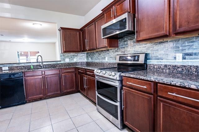 3412 Spruce St, Royse City, TX 75189 - kitchen featuring stainless steel appliances, dark stone countertops, light tile patterned flooring, backsplash, and a sink