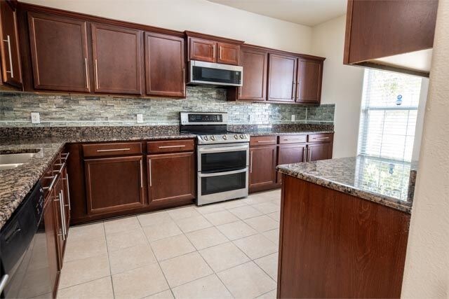 3412 Spruce St, Royse City, TX 75189 - kitchen with appliances with stainless steel finishes, tasteful backsplash, dark stone counters, and light tile patterned floors