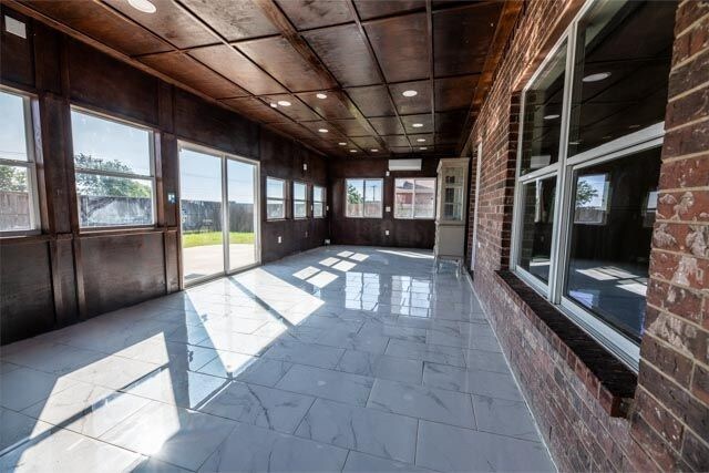 3412 Spruce St, Royse City, TX 75189 - unfurnished sunroom with marble look tile flooring, brick wall, and recessed lighting