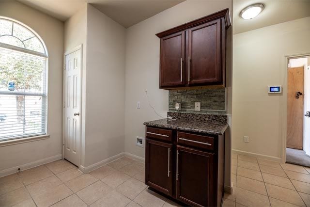 3412 Spruce St, Royse City, TX 75189 - kitchen featuring light tile patterned floors, dark stone countertops, decorative backsplash, baseboards, and dark brown cabinets