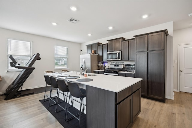 2028 Saddle Way, Mesquite, TX 75149 - kitchen featuring appliances with stainless steel finishes, an island with sink, a sink, a breakfast bar area, and light wood-style floors