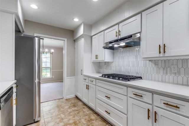 4023 Candlenut Ln, Dallas, TX 75244 - kitchen with under cabinet range hood, appliances with stainless steel finishes, white cabinets, backsplash, and a chandelier