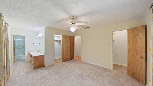 1015 Monte Carlo Dr, Grand Saline, TX 75140 - unfurnished bedroom featuring a walk in closet, a closet, light colored carpet, a textured ceiling, and a ceiling fan