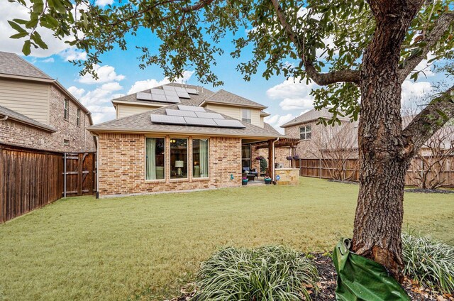 917 Navasota Trl, Mckinney, TX 75071 - rear view of house featuring roof with shingles, brick siding, solar panels, and a patio area