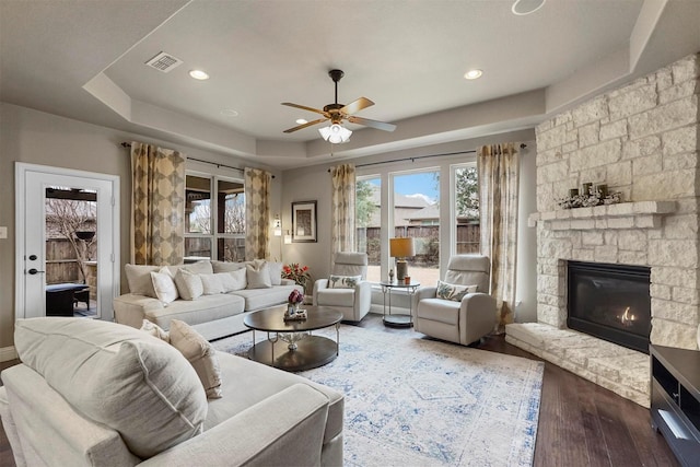 917 Navasota Trl, Mckinney, TX 75071 - living room featuring a tray ceiling, wood finished floors, ceiling fan, a stone fireplace, and recessed lighting
