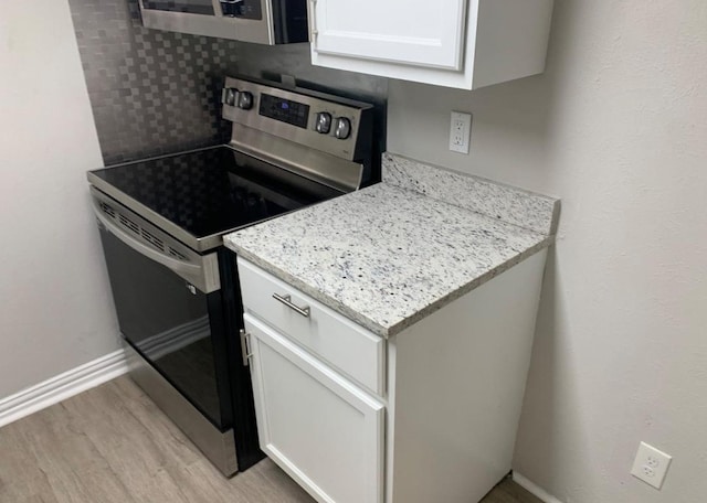 6600 Eastridge Dr Unit 117, Dallas, TX 75231 - kitchen with appliances with stainless steel finishes, light wood finished floors, white cabinets, and light stone counters