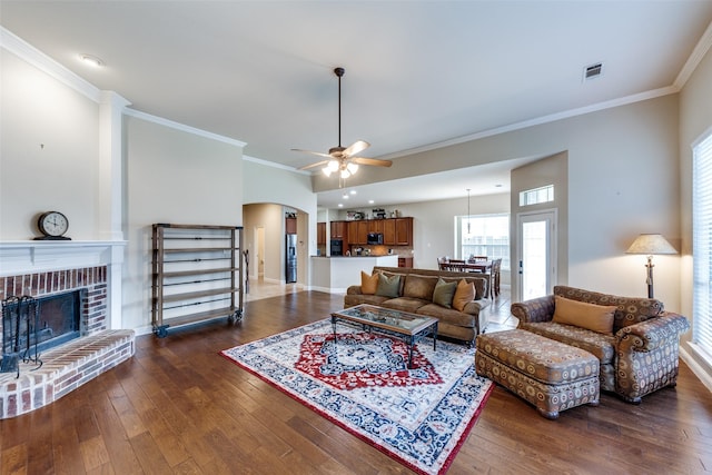 1616 Teakwood Dr, Wylie, TX 75098 - living room with dark wood-type flooring, arched walkways, crown molding, a ceiling fan, and a brick fireplace