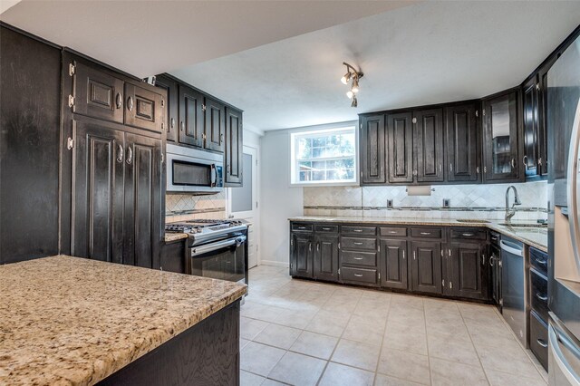 141 Stonegate Ct, Bedford, TX 76022 - kitchen with stainless steel appliances, decorative backsplash, light tile patterned floors, glass insert cabinets, and a sink