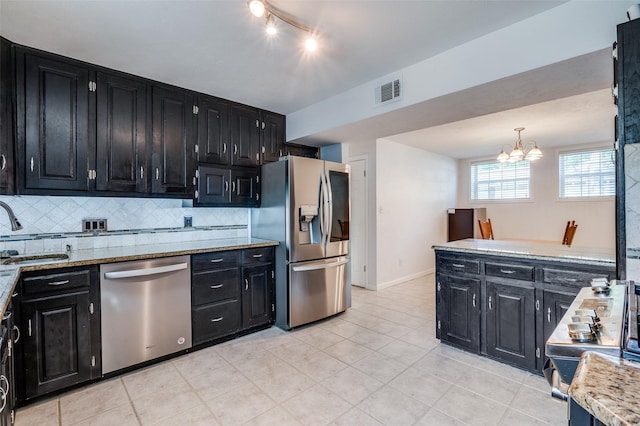 141 Stonegate Ct, Bedford, TX 76022 - kitchen featuring dark cabinetry, stainless steel appliances, a sink, backsplash, and a chandelier