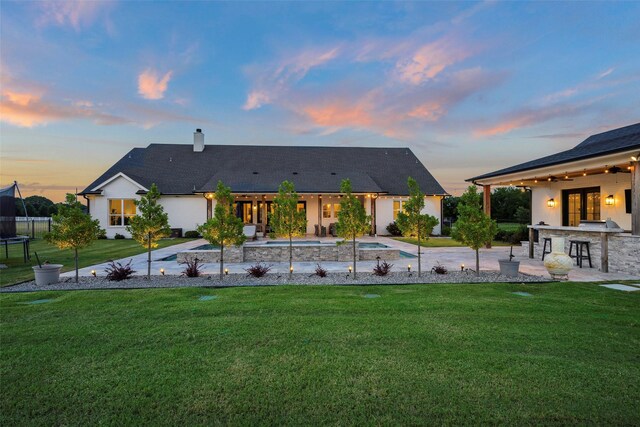 36 Mirror Lakes Ct, Gunter, TX 75058 - back of property at dusk featuring an in-ground hot tub, a trampoline, french doors, a chimney, and a lawn