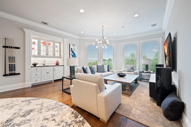 504 Bristol Dr, Allen, TX 75013 - living room featuring dark wood finished floors, bar with sink, a chandelier, ornamental molding, and recessed lighting