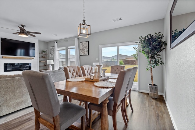 512 Leeward Ln, Crowley, TX 76036 - dining space featuring ceiling fan, wood finished floors, baseboards, and a glass covered fireplace