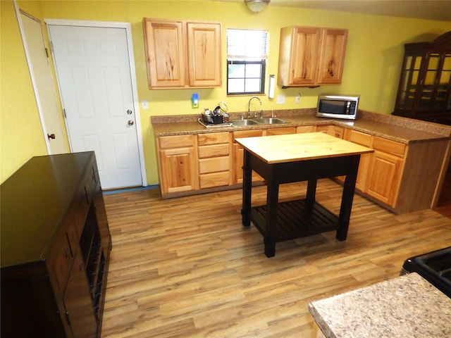 225 County Road 472, Ranger, TX 76470 - kitchen featuring a sink, stainless steel microwave, light wood finished floors, a peninsula, and light brown cabinetry