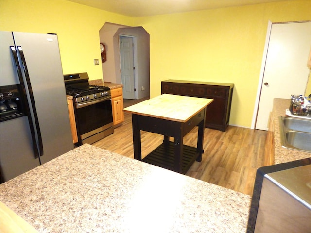 225 County Road 472, Ranger, TX 76470 - kitchen featuring stainless steel appliances, arched walkways, a sink, light countertops, and light wood finished floors