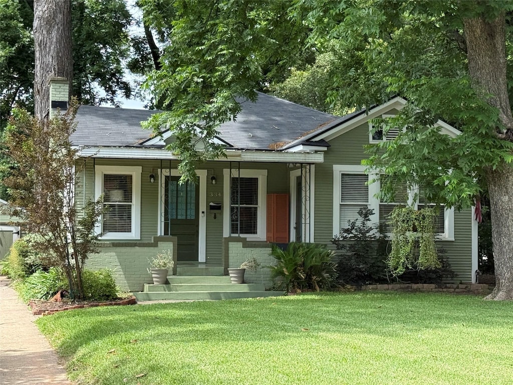 334 Ockley Dr, Shreveport, LA 71105 - bungalow-style house with a chimney, a front lawn, roof with shingles, and brick siding