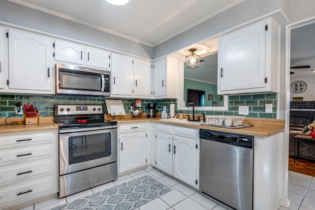 1434 Southland St, Sulphur Springs, TX 75482 - kitchen featuring stainless steel appliances, crown molding, a sink, light tile patterned floors, and white cabinetry