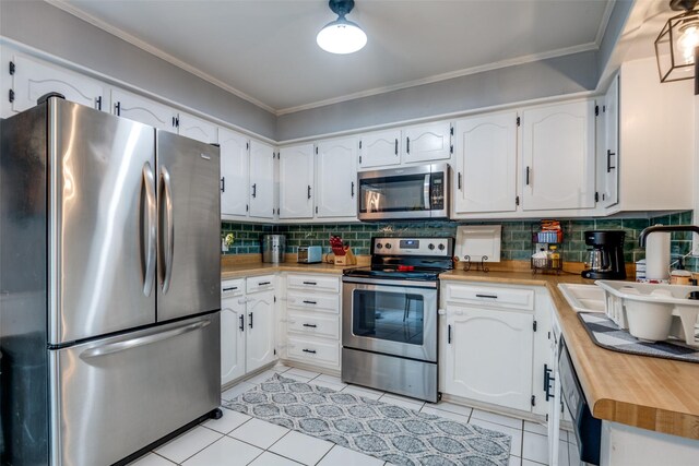 1434 Southland St, Sulphur Springs, TX 75482 - kitchen featuring stainless steel appliances, butcher block counters, decorative backsplash, white cabinetry, and ornamental molding