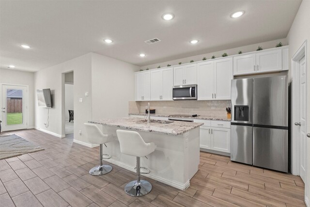 620 Ruthye Ln, Pilot Point, TX 76258 - kitchen with stainless steel appliances, a sink, wood finish floors, backsplash, and a center island with sink