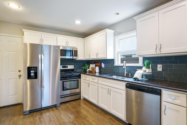 4731 Wateka Dr, Dallas, TX 75209 - kitchen with stainless steel appliances, a sink, white cabinets, dark wood-type flooring, and recessed lighting