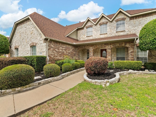 6915 Westside Pl, Sachse, TX 75048 - view of front facade with stone siding, roof with shingles, a front yard, and brick siding