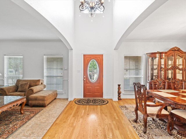 6915 Westside Pl, Sachse, TX 75048 - entryway with arched walkways, a chandelier, ornamental molding, wood finished floors, and baseboards