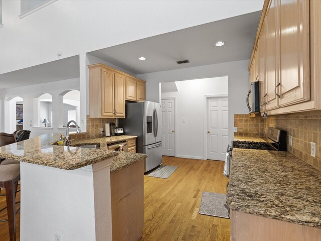 6915 Westside Pl, Sachse, TX 75048 - kitchen featuring a sink, appliances with stainless steel finishes, light brown cabinets, a kitchen breakfast bar, and light stone countertops