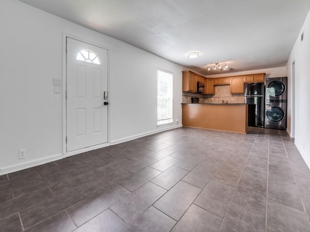 5234 Fleetwood Oaks Ave Unit 120, Dallas, TX 75235 - kitchen with black appliances, stacked washer / dryer, dark tile patterned floors, decorative backsplash, and open floor plan