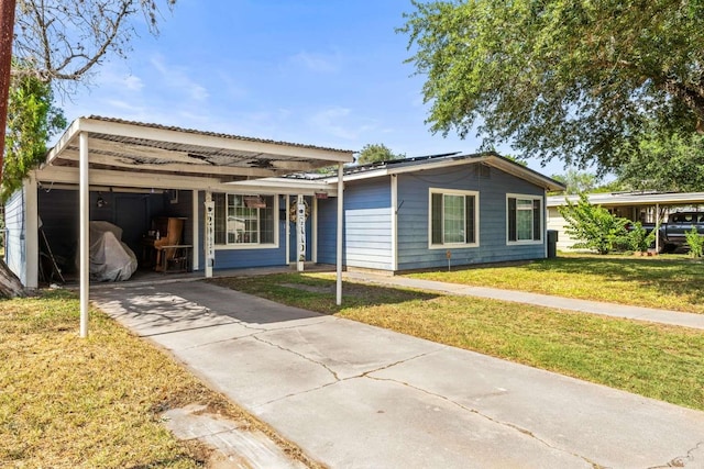 1011 Kleberg St, Alice, TX 78332 - ranch-style home featuring a front lawn, driveway, an attached carport, and solar panels