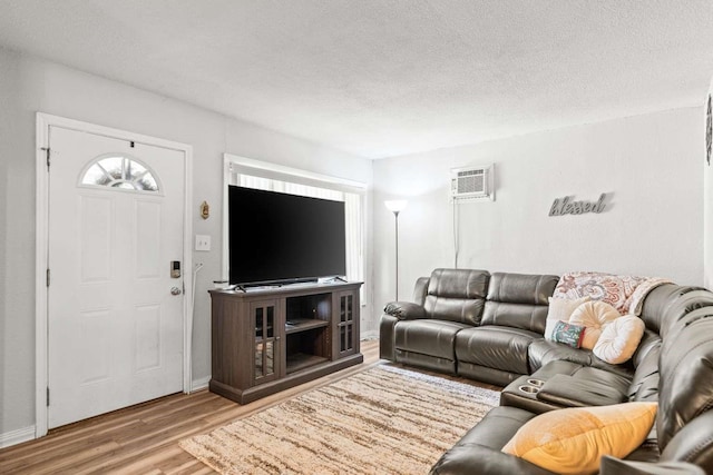 1011 Kleberg St, Alice, TX 78332 - living area featuring an AC wall unit, wood finished floors, a textured ceiling, and baseboards