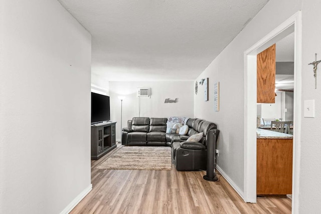 1011 Kleberg St, Alice, TX 78332 - living area with light wood-style flooring, an AC wall unit, and baseboards