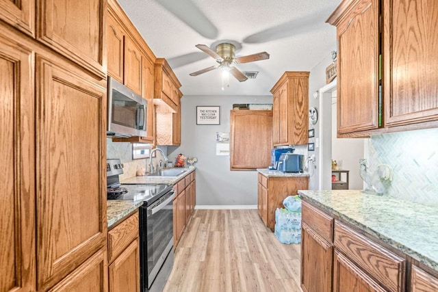 1011 Kleberg St, Alice, TX 78332 - kitchen with stainless steel appliances, a sink, light wood finished floors, ceiling fan, and tasteful backsplash
