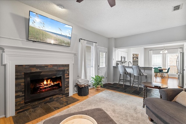 736 Fawn Valley Dr, Allen, TX 75002 - living area featuring wood finished floors, a ceiling fan, a fireplace with flush hearth, and a textured ceiling