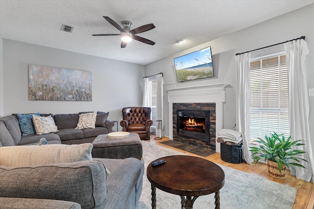 736 Fawn Valley Dr, Allen, TX 75002 - living area with wood finished floors, ceiling fan, a fireplace with flush hearth, healthy amount of natural light, and a textured ceiling