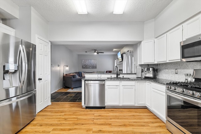 736 Fawn Valley Dr, Allen, TX 75002 - kitchen featuring stainless steel appliances, a sink, light wood-style floors, open floor plan, and a textured ceiling