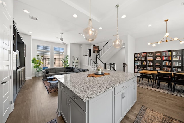 1844 Stevens Bluff Ln, Dallas, TX 75208 - kitchen with recessed lighting, light stone countertops, a kitchen island, wood finished floors, and decorative light fixtures