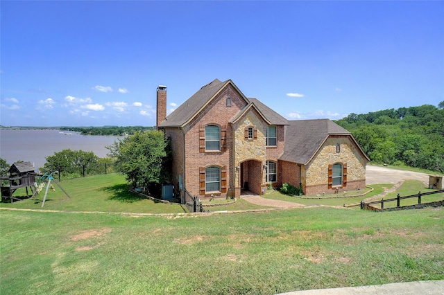 809 Cimmarron Bay Dr, Runaway Bay, TX 76426 - french country home featuring a chimney, brick siding, a water view, stone siding, and roof with shingles