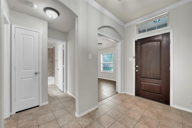 1209 Evers Dr, Mckinney, TX 75071 - foyer featuring light tile patterned floors, ornamental molding, baseboards, and arched walkways