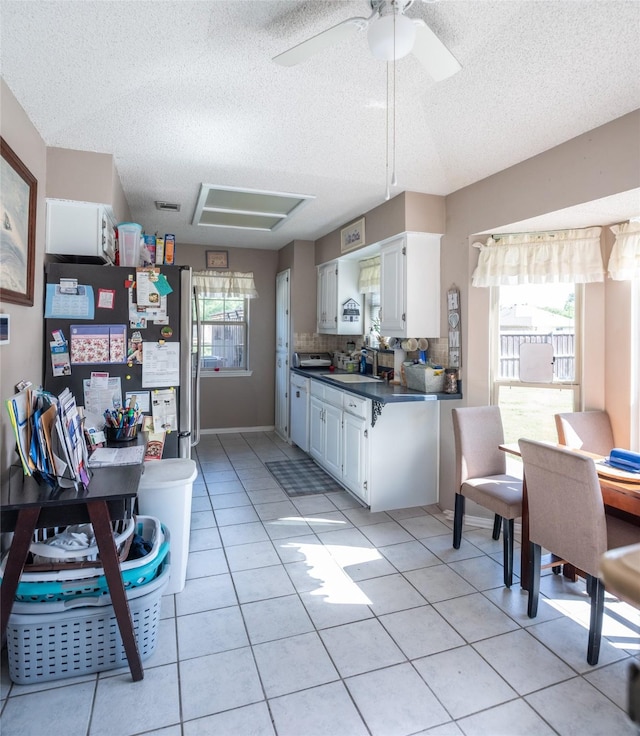 3506 Bryan St, Sachse, TX 75048 - kitchen featuring dark countertops, light tile patterned floors, freestanding refrigerator, a textured ceiling, and white cabinetry